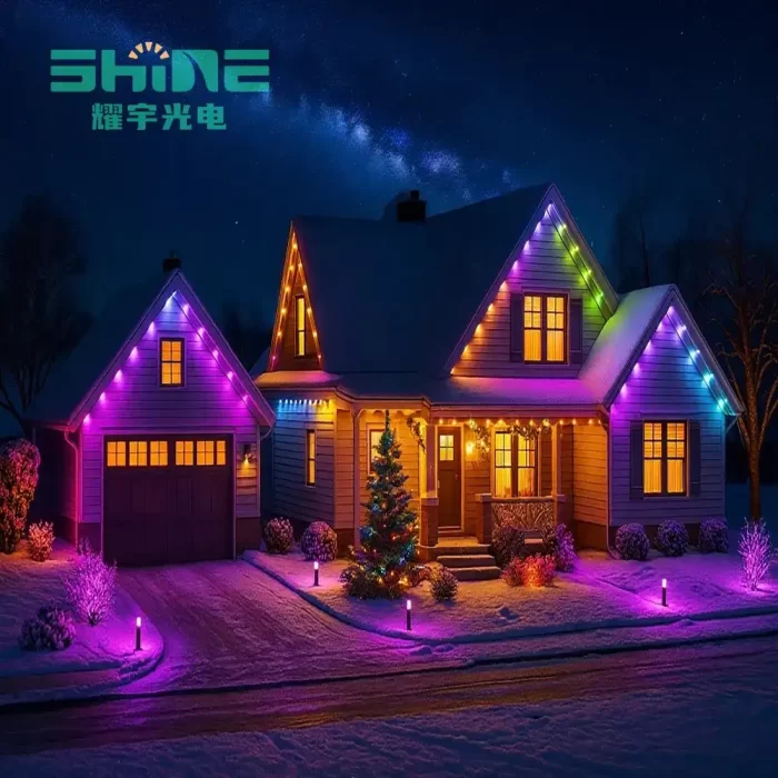 Colorful LED eaves lights installed on a snowy two-story house with Christmas decorations at night.