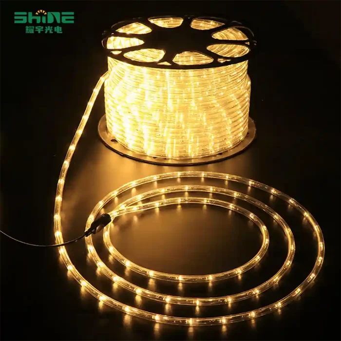 LED string lights wrapped in precise circular coils around a black support, glowing warmly on a dark background.