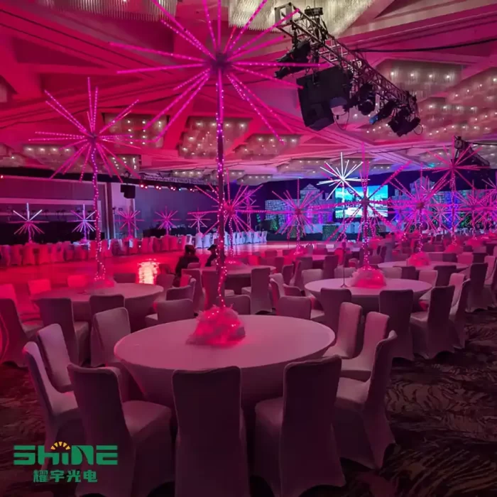 Large-scale indoor wedding venue decorated with LED string lights for weddings in a 3D firework shape, mounted on banquet tables and ceiling trusses for immersive celebration lighting.
