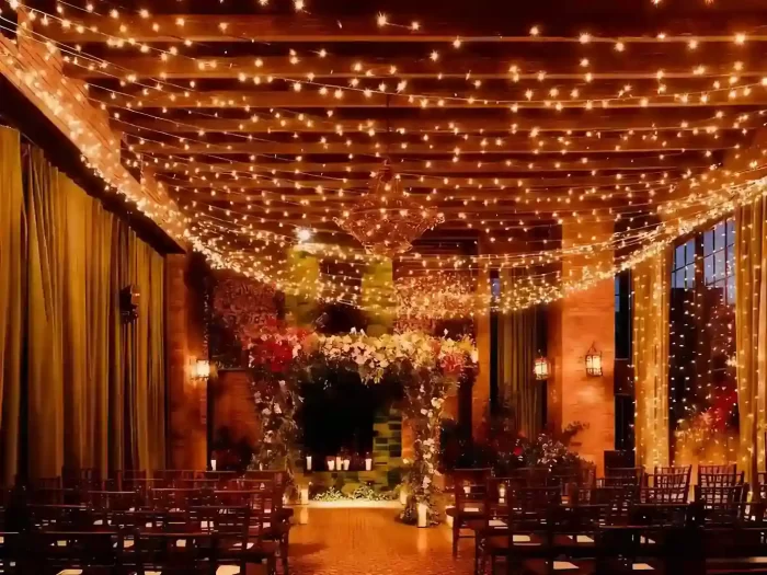 string light ceiling canopy in a ceremony hall with a wall light curtain and floral arch, warm wedding ambience.
