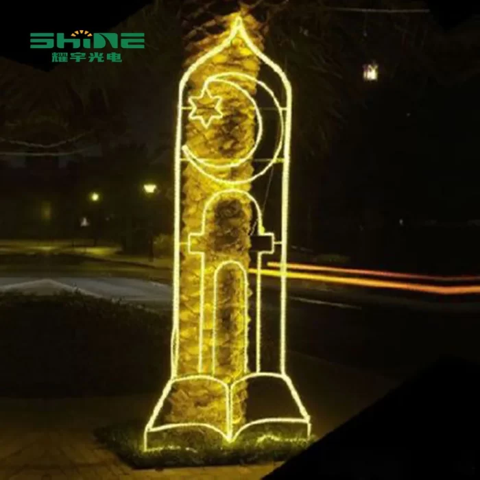 A tall, gold-colored LED light 2d motif light shaped like a spire with a crescent moon, stars, and an open book design at the base.