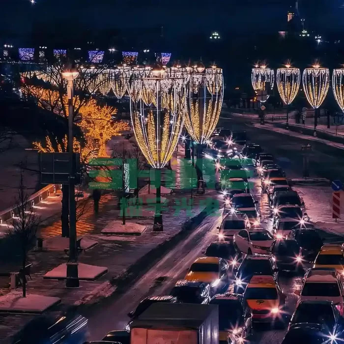 Elegant, goblet-shaped golden motif lights line a snow-covered city street at night, casting a warm glow over the winter traffic below.