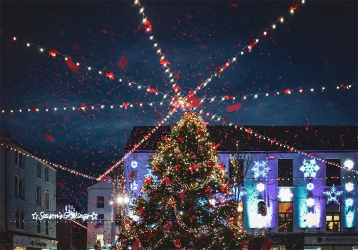 Town square Christmas light show with a 3D LED motif tree and overhead festive string lights