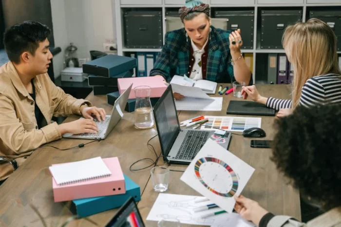 Project team sitting around a table with laptops and printed color charts, reviewing quotes and technical specifications for 3D LED motif light installations