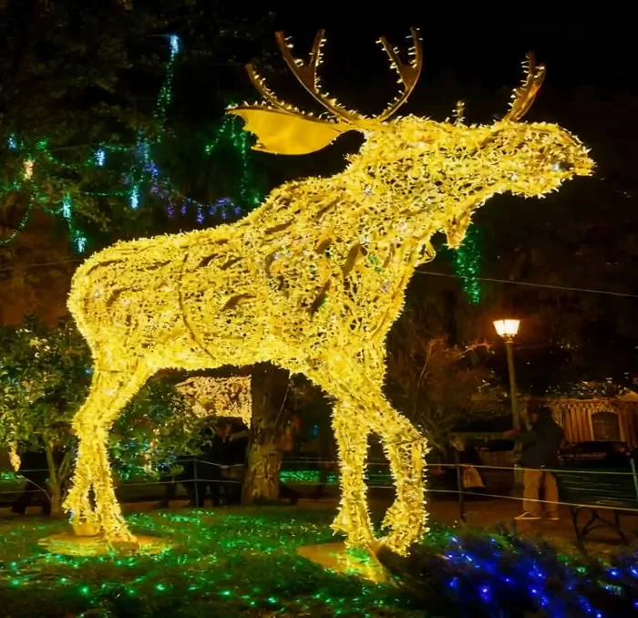 Golden 3D LED reindeer motif light sculpture installed in a city park at night