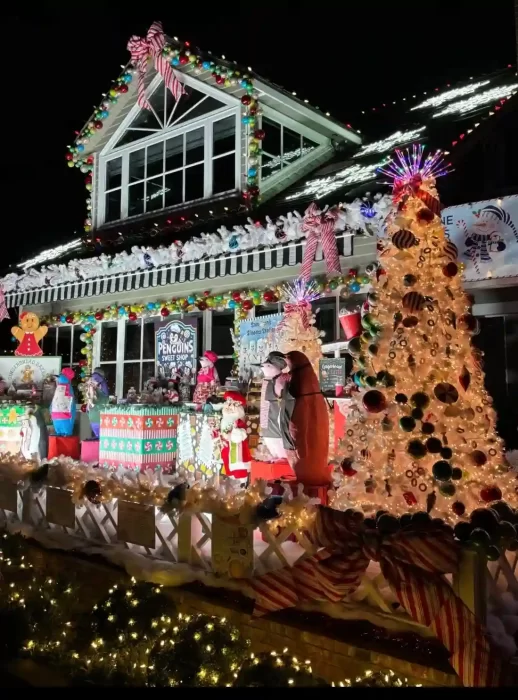 House front decorated for Christmas with candy-themed garlands, illuminated trees and multiple character motifs creating a bright festive scene