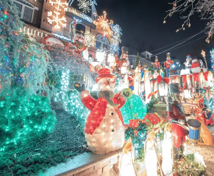 Colorful custom 3D snowman LED motif light and outdoor Christmas sculptures decorating a house front yard at night