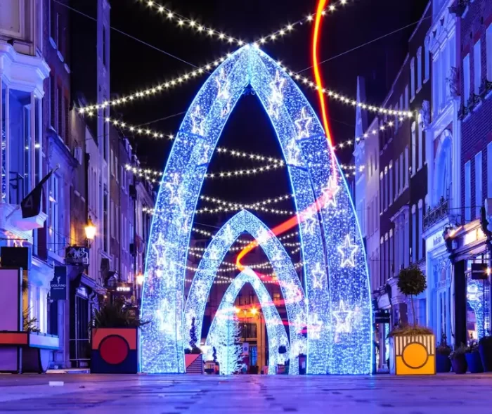 Large blue 3D motif arch lights with star patterns installed along a pedestrian shopping street at night, showing a city-centre decorative lighting project.
