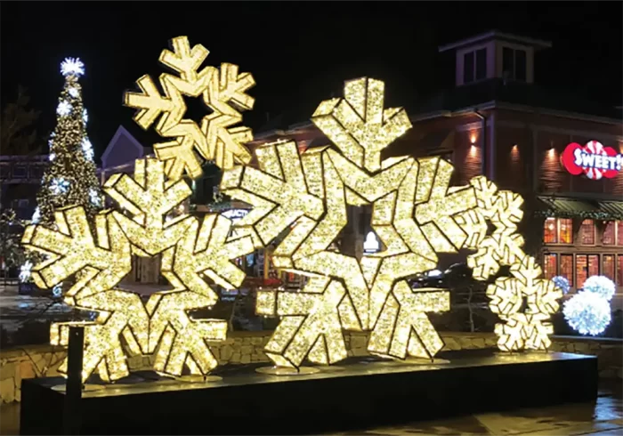 Large 3D LED snowflake motif lights in a commercial outdoor Christmas display at night