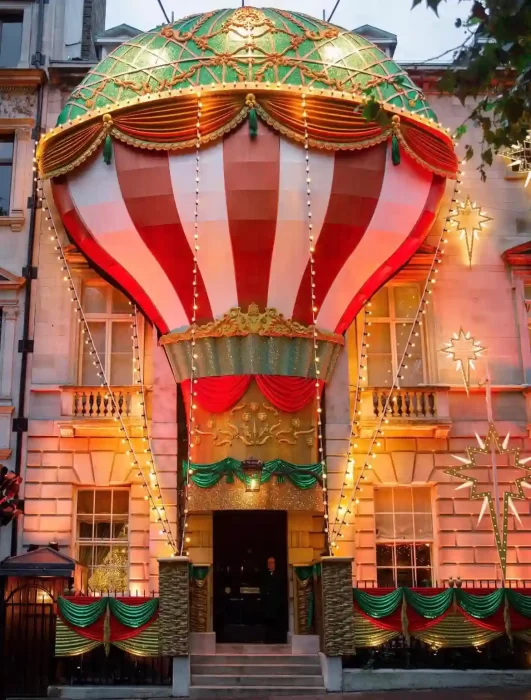 Elegant city building entrance transformed into a giant hot air balloon motif with draped fabric and warm Christmas string lights