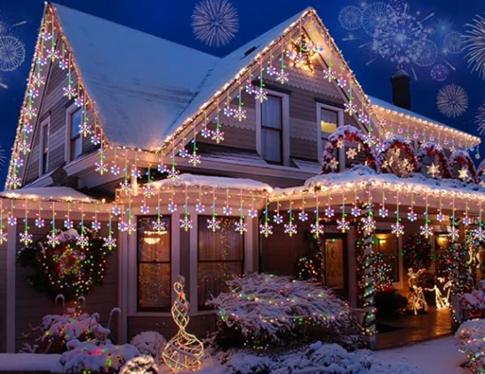 A house adorned with a variety of colorful LED Christmas lights, with hanging snowflake designs.