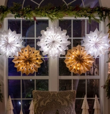 Warm white and cool white snowflake motif Christmas lights hanging in a living room window to create a cozy holiday display.