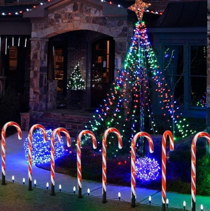 Candy cane pathway markers with a tree decorated with LED lights, adding holiday charm to a front yard.