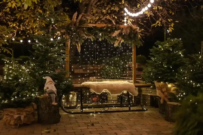 Outdoor holiday patio with warm fairy lights, evergreen trees, and a decorative sled