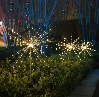 Warm white LED firework lights on ground stakes installed in a garden, ideal for outdoor wedding ceremony aisles