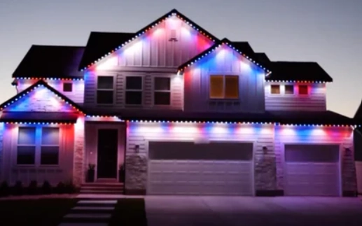 Modern house facade outlined with RGB roofline LED lights, creating a color-changing holiday motif at dusk.
