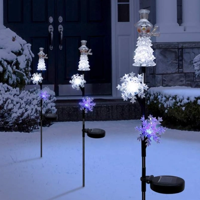 Snowflake and tree-shaped LED lights arranged along a snowy garden, creating a winter wonderland effect.