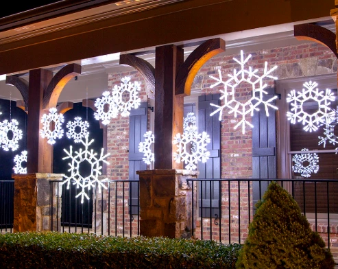 White snowflake decorations hanging on a porch, creating a stunning, symmetrical display.