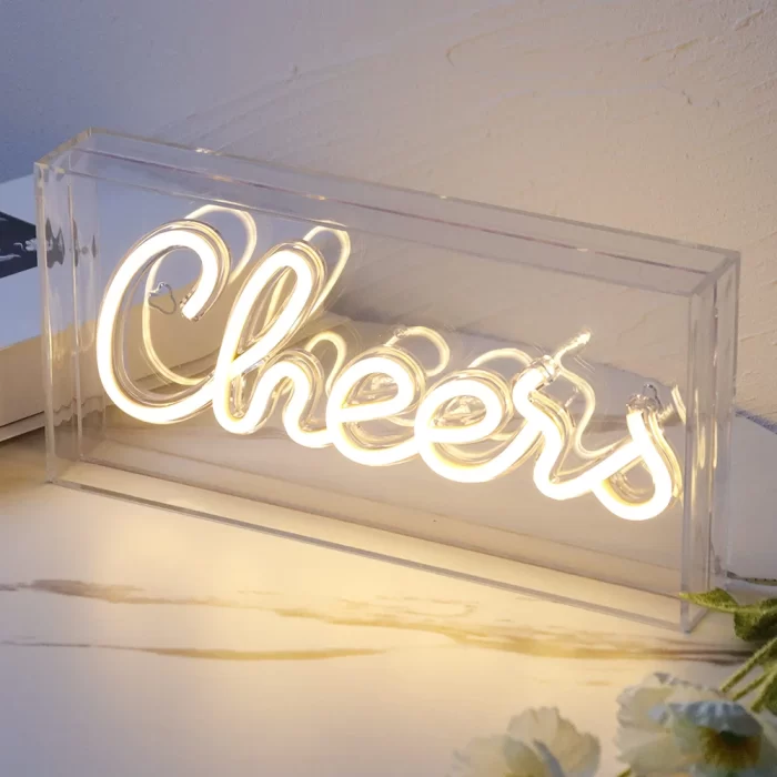 Warm white neon script reading “Cheers” in a clear acrylic display, reinforcing positive feelings through repeated motif exposure