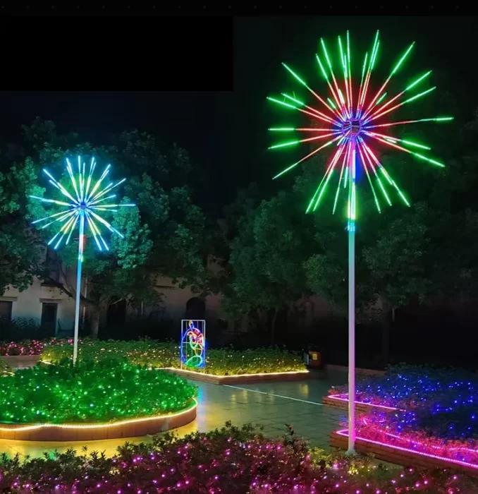 RGB LED firework lights installed in a landscaped hotel courtyard, showing colorful pole-mounted starburst fixtures for permanent outdoor decoration.